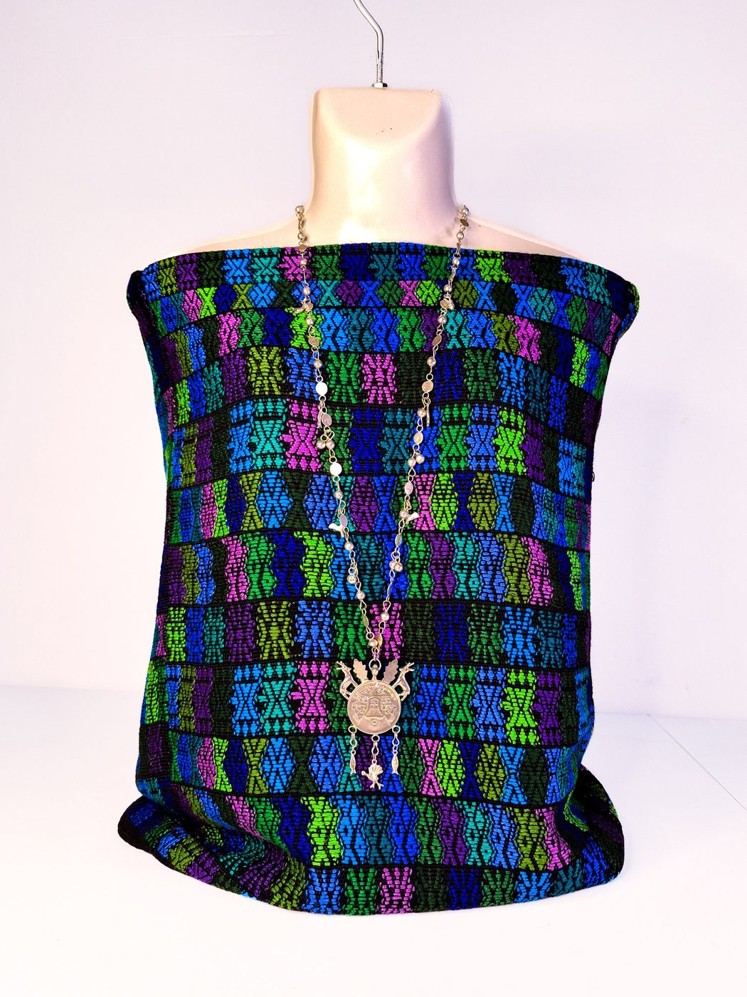 Textil con bloques de color en azul, verde, magenta y negro colocado sobre un maniquí